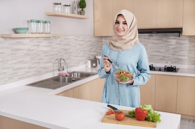 Hijab da portare della bella giovane donna che prepara insalata di verdure