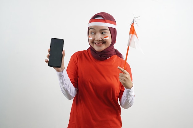 Hijab Donna che tiene la bandiera dell'Indonesia che mostra il telefono vuoto