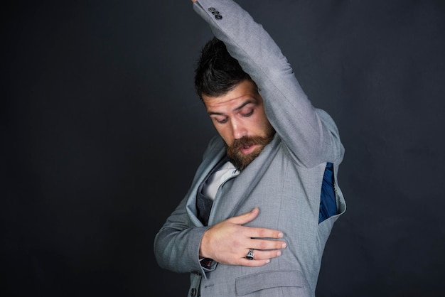 Hipster con barba con foro strappato sulla cucitura. La modella indossa una taglia piccola. L'uomo barbuto guarda con sorpresa il cappotto strappato. Abbigliamento contraffatto e contraffatto. Concetto di cattiva qualità