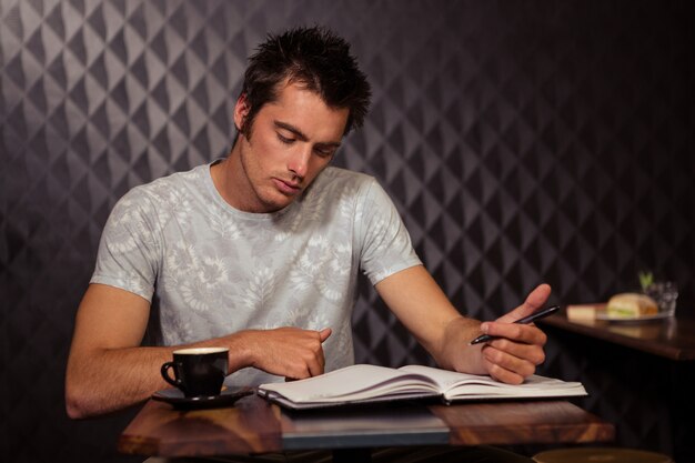 Hipster con caffè e la scrittura in planner