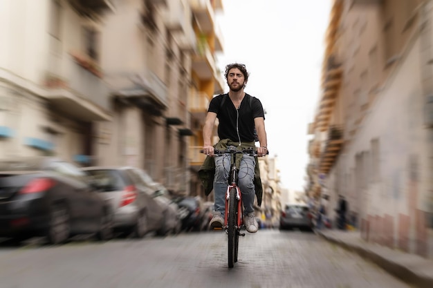 Hipster con gli auricolari passeggiando con la bicicletta nel centro della città