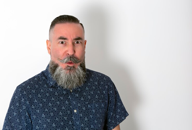 Photo hipster dengan kemeja bunga, janggut dan kumis besar close up dengan wajah terkejut di atas putih