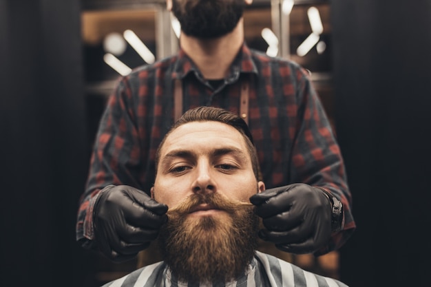 Hipster giovane bell'uomo visitando un barbiere. Stile e taglio della barba alla moda ed eleganti.