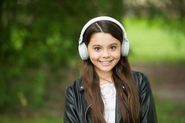 Hipster ragazza ascolto musica moderna cuffie natura sfondo audio libro concetto