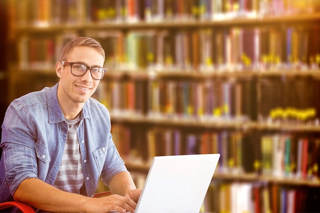 Hipster sul computer portatile contro il primo piano di una libreria