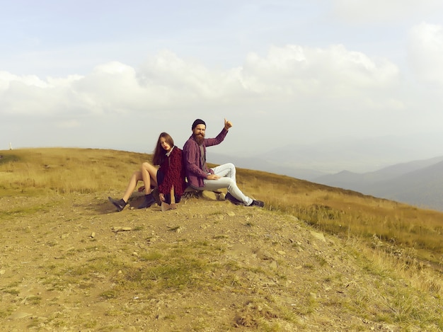 Hipsters delle coppie che si siedono sulla pietra sulla cima della montagna