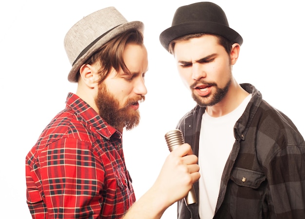 Hipsters due giovani uomini che cantano con il microfono isolato su bianco