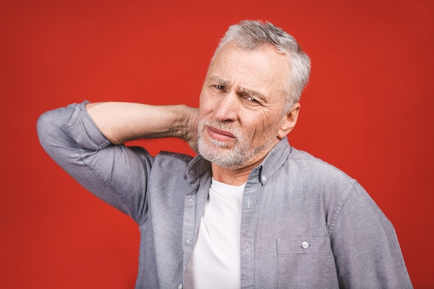 Ho bisogno di un massaggio. Uomo senior frustrato in mano della tenuta dell'abbigliamento casual sul suo collo mentre stando.