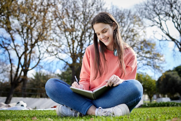 Ho già alcune idee per il mio compito. Inquadratura di una studentessa che scrive sul suo taccuino mentre è seduta fuori