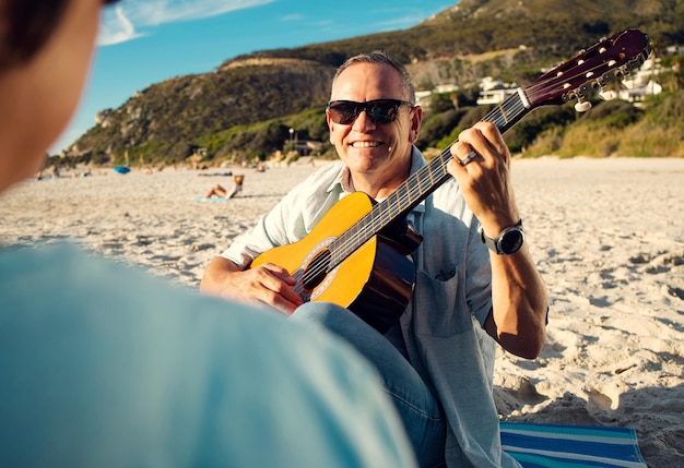 Ho scritto questa canzone appositamente per te. Inquadratura di un uomo che suona la chitarra mentre era in spiaggia con sua moglie