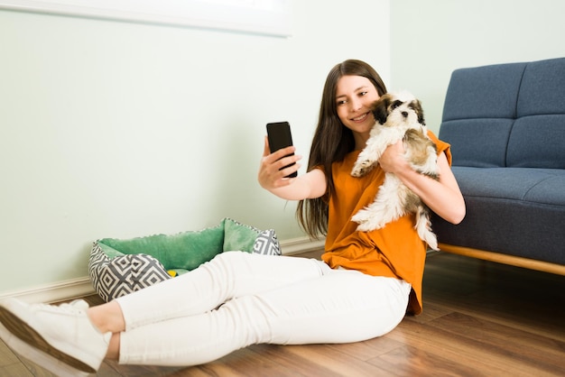 Ho un nuovo cucciolo! Eccitata donna caucasica che si fa un selfie con il suo bellissimo cane shih tzu per pubblicare la foto sui suoi social media