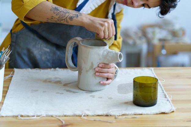 Hobby di ceramica o fabbricazione di ceramica piccola impresa giovane artista brocca di stampaggio di argilla grezza in studio