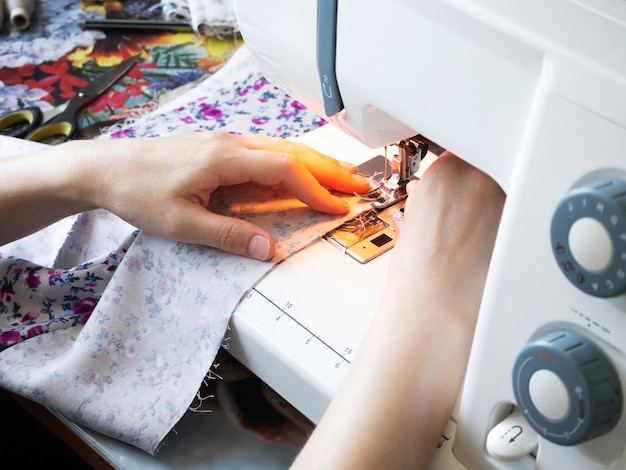 Hobby e concetto fatto a mano stare a casa concetto mani femminili primo piano cucire su una macchina da cucire domestica