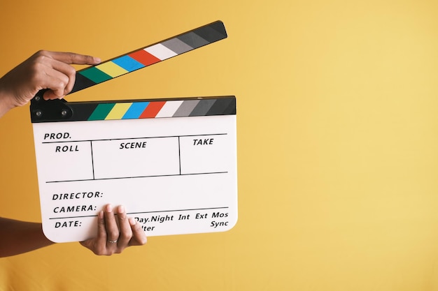 Holding Movie clapper board contro il muro bianco