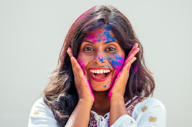 Holi Festival Of Colors Ritratto di felice ragazza indiana in holi color che balla e si diverte sullo sfondo bianco dello studio della parete