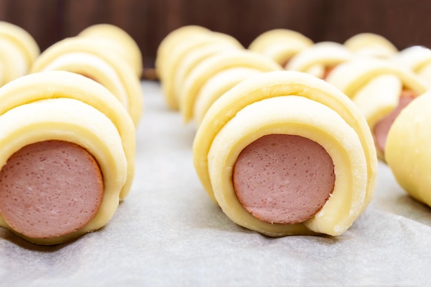 Home Baking Salsiccia nell'impasto Molti panini crudi su un reticolo Primo piano