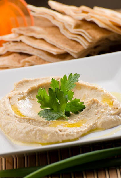 Hommos, labneh, chancliche, pasta all'aglio, cibo arabo su piatto bianco con tessuto arancione sullo sfondo