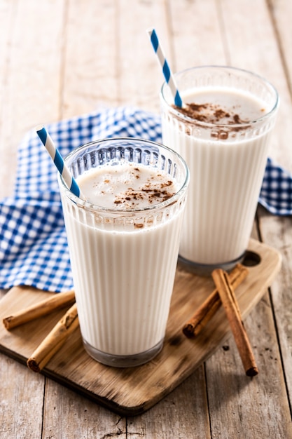 Horchata fresca con cannella in vetro sulla tavola di legno rustica