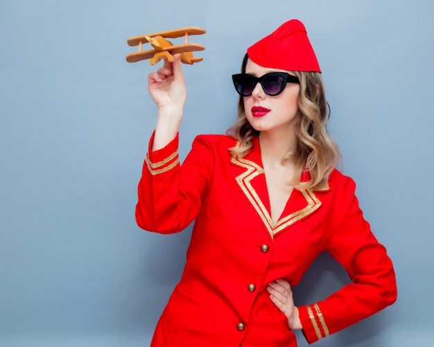 hostess che indossa in uniforme rossa con aeroplano di legno