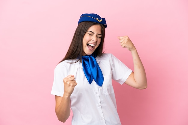 Hostess dell'aeroplano donna brasiliana isolata su sfondo rosa che celebra una vittoria