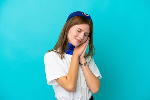 Hostess dell'aeroplano Donna inglese isolata su sfondo blu che fa il gesto del sonno in un'espressione adorabile