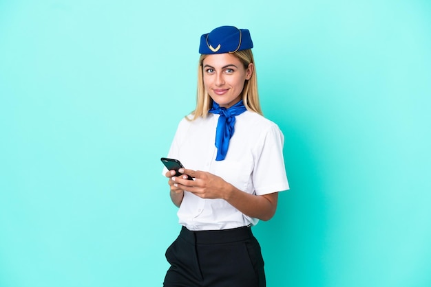 Hostess dell'aeroplano Donna uruguaiana isolata su sfondo blu che invia un messaggio con il cellulare