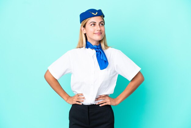 Hostess dell'aeroplano Donna uruguaiana isolata su sfondo blu in posa con le braccia all'anca e sorridente