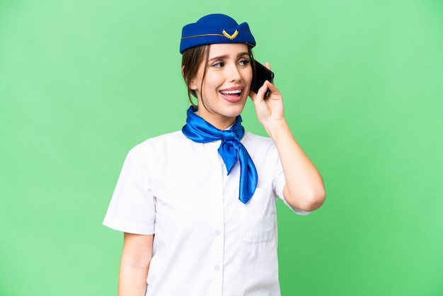 Hostess dell'aeroplano su sfondo chroma key isolato mantenendo una conversazione con il telefono cellulare