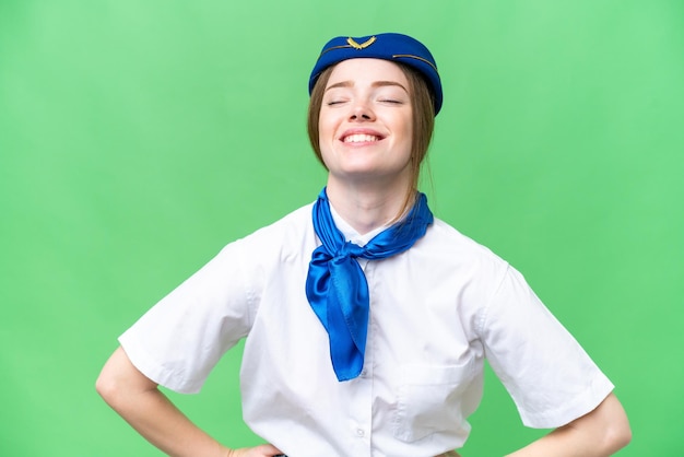 Hostess di aeroplano su sfondo chroma key isolato in posa con le braccia all'anca e sorridente