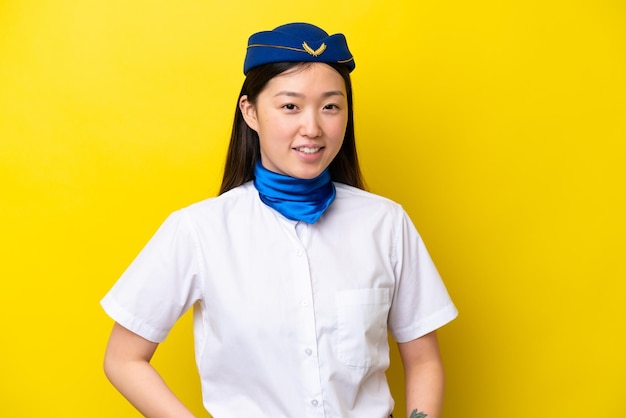 Hostess donna cinese dell'aeroplano isolata su sfondo giallo ridendo