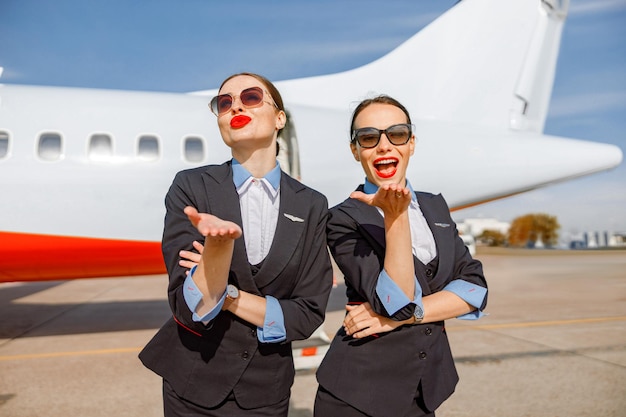 Hostess donne allegre che inviano baci all'aeroporto