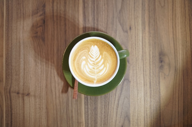 Hot Art Latte nella tazza verde sul tavolo di legno