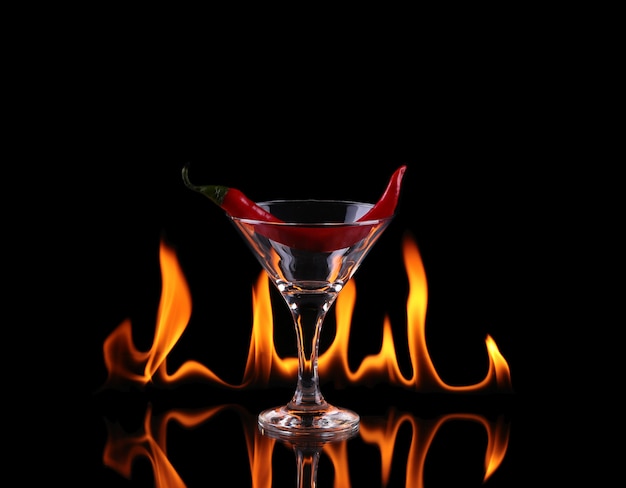 Hot chili pepper in un bicchiere da martini con un fuoco su uno sfondo nero