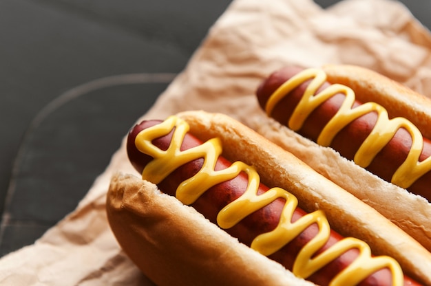 Hot dog alla griglia con barbecue con senape americana gialla, su uno sfondo di legno scuro