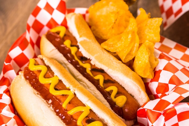 Hot dog alla griglia con senape e ketchup sul tavolo con birra alla spina.