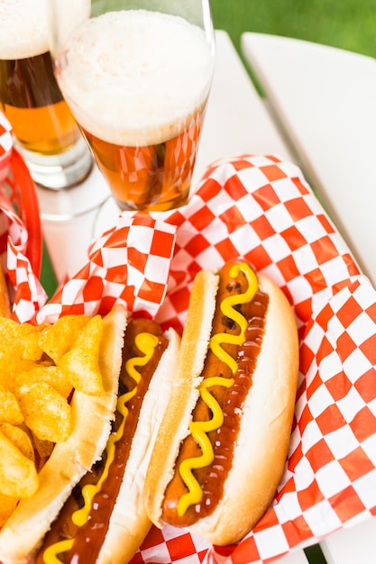 Hot dog alla griglia con senape e ketchup sul tavolo con birra alla spina.