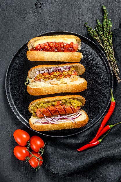 Hot dog completamente caricati con condimenti assortiti su un vassoio.