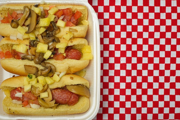 Hot dog con ananas e funghi in un piatto di plastica usa e getta.