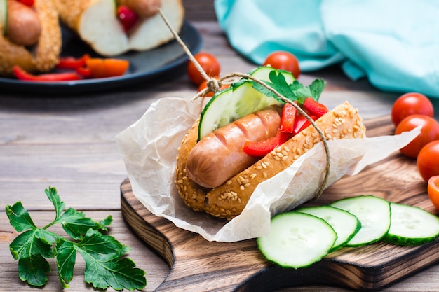 hot dog con panini al sesamo e verdure fresche su un piatto su un tavolo di legno