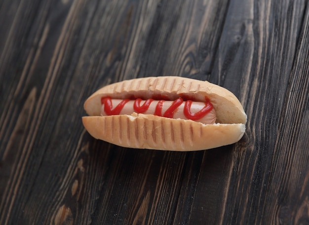 Hot dog con salsa di pomodoro su fondo di legno scuro.foto con spazio di copia.