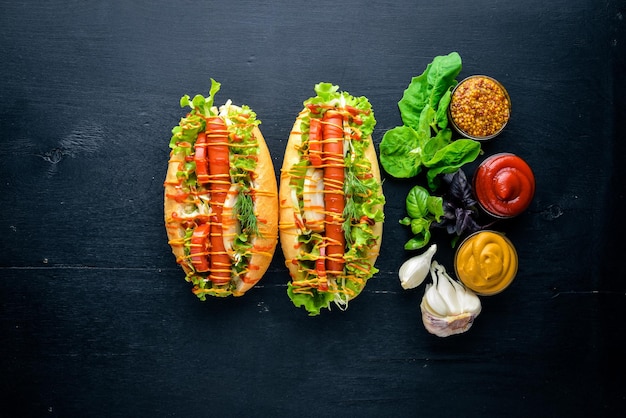 Hot dog con salsiccia alla griglia senape e ketchup cipolle e verdure su sfondo di legno Vista dall'alto Spazio libero