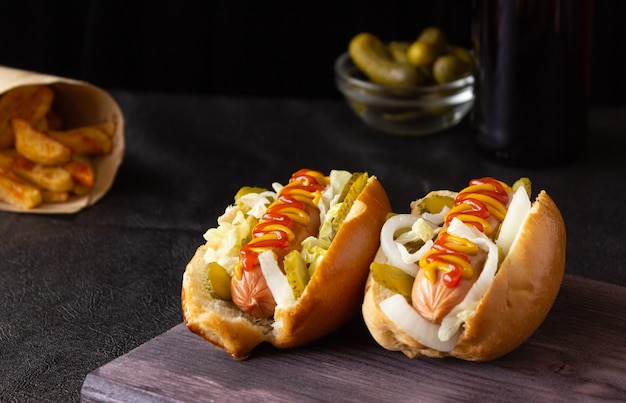 Hot dog con verdure, senape e ketchup su un tagliere su sfondo scuro