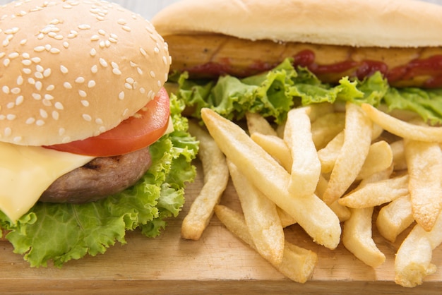 Hot dog, hamburger e patatine fritte sul tavolo di legno.