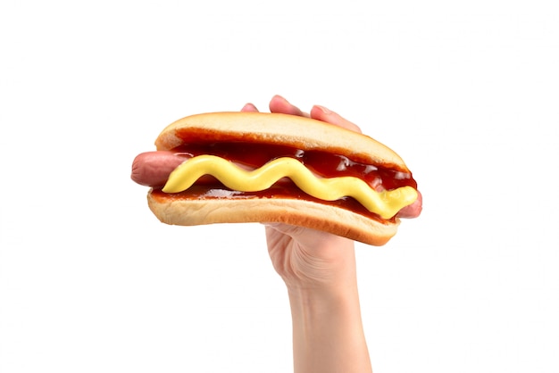 Hot dog in mano della donna isolata su fondo bianco. Copia spazio.