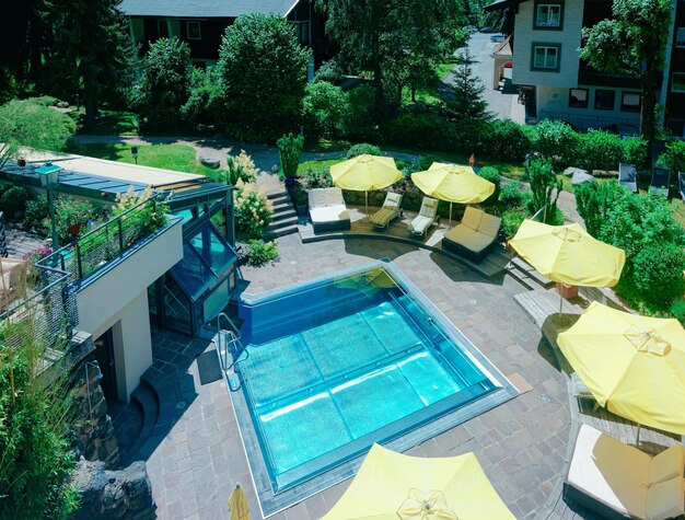 Hotel moderno con piscina con ombrelloni gialli su sfondo blu. A bordo piscina per il relax. Divertimento estivo e architettura edilizia. Vacanze e vacanze in villa durante il viaggio o il tempo libero.