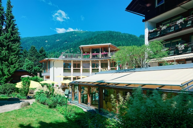 Hotel resort per famiglie e paesaggio con la natura in estate in Austria. Design moderno della casa in legno tra le montagne. Facciata esterna del complesso edilizio. Vista frontale della villa. Rilassati in vacanza.