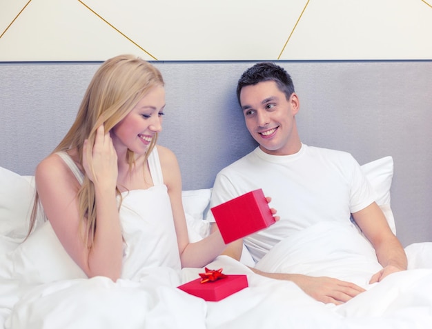 hotel, viaggi, relazioni, vacanze e concetto di felicità - l'uomo dà alla donna una piccola scatola regalo rossa