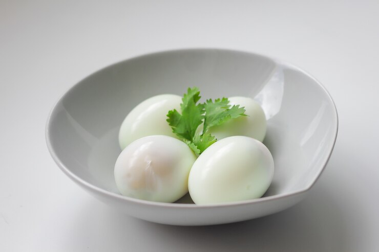 Huevos cocidos sin cortar sobre un bol blanco, comida en casa