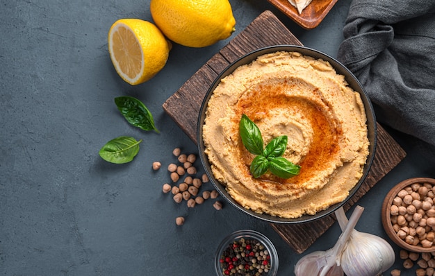 Hummus con olio di oliva alla paprika e basilico su sfondo grigioblu