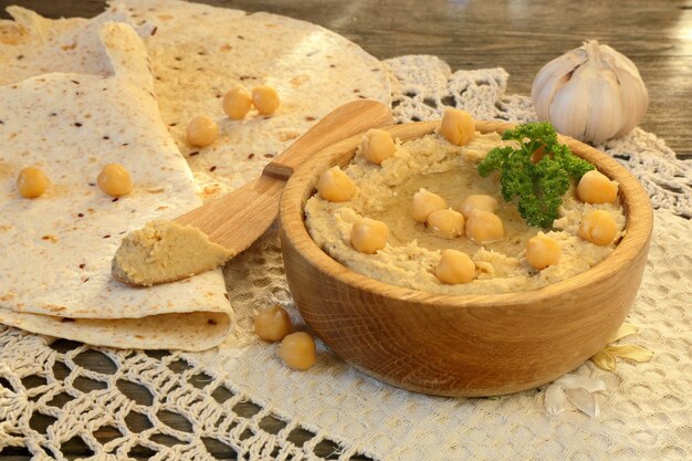 Hummus con pane pita e aglio su un tavolo di legno